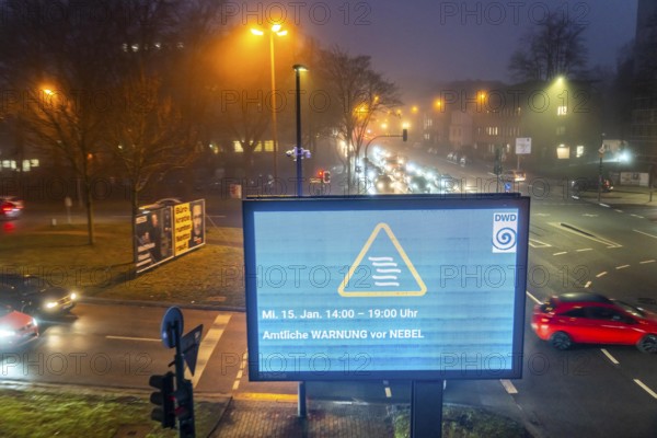 Dense fog, with visibility partly below 100 metres, city centre traffic at rush hour on Alfredstraße, B224, official warning of fog, digital billboard, advertising board, in Essen, North Rhine-Westphalia, Germany, Europe