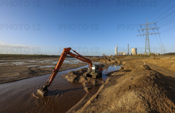 Dinslaken, North Rhine-Westphalia, Germany, New Emscher estuary into the Rhine. Excavator in the construction site of the new Emscher estuary in front of the decommissioned STEAG Voerde coal-fired power station. The mouth of the Emscher into the Rhine is being moved almost 500 metres north from Dinslaken to Voerde. Fish will then be able to swim barrier-free up the new Emscher from the Rhine through a newly created floodplain area. Following the construction of a parallel sewer, the Emscher has been completely free of sewage since January 2022. The river was previously an open, above-ground combined sewer with rainwater and wastewater, Europe