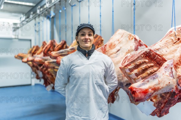 Three quarter length frontal portrait of a proud and happy woman butcher in a meat processing factory