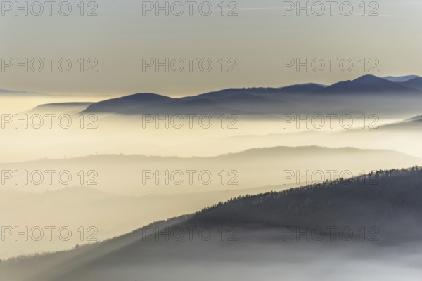 The mountains are shrouded in mist and the sky is a mixture of blue and white. The bleak atmosphere lends the scene a serene and peaceful mood. Bas rhin, Alsace, France, Europe