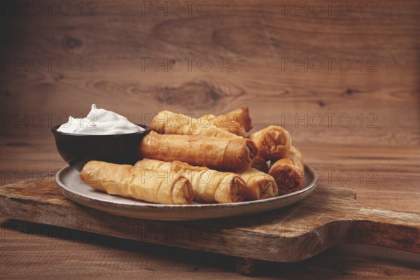 Fried spring rolls with cheese, on a wooden background, with cream sauce, no people