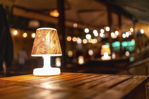 Soft, warm lighting creates a cozy atmosphere at a rustic wedding venue, highlighting elegant wooden tables and a charming lampshade design