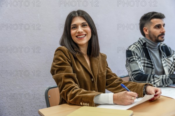 Smiling female student taking notes in class at university, fully engaged in learning and focused on her academic success