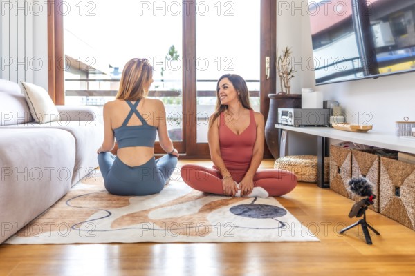 Two fitness trainers recording online yoga and meditation class in their living room using a microphone