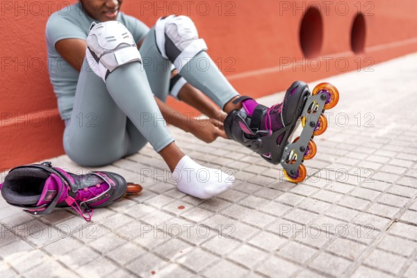 Cropped photo of part of an unrecognizable african woman putting on inline skates sitting on the street