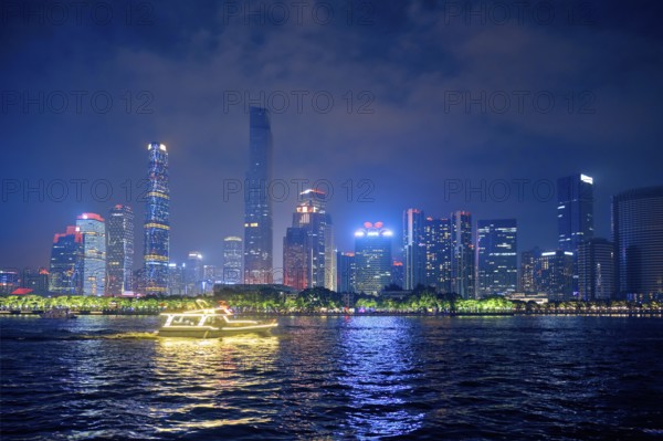 Guangzhou cityscape skyline over the Pearl River with tourist boat illuminated in the evening. Guangzhou, China, Asia