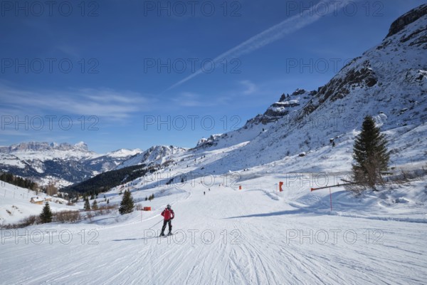 View of a ski resort piste with people skiing in Dolomites in Italy. Canazei, Italy, Europe
