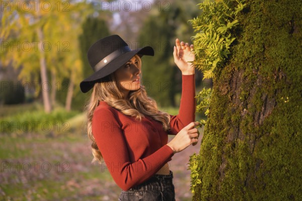 Lifestyle, portrait of a caucasian girl in a black hat at sunset in a green park