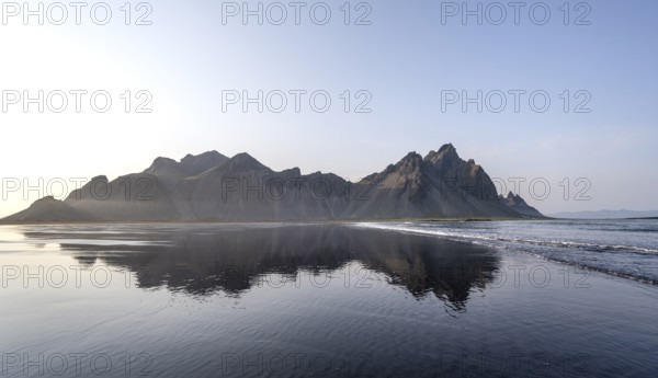Black lava beach, sandy beach and sea, mountains Klifatindur reflected in the water, Eystrahorn and Kambhorn, headland Stokksnes, mountain range Klifatindur, Austurland, East Iceland, Iceland, Europe