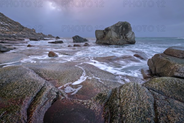 Rocks on beach of fjord of Norwegian sea in winter on sunset. Utakliev beach, Lofoten islands, Norway, Europe