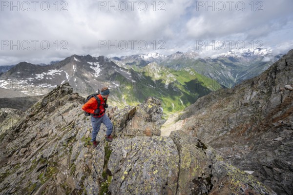 Mountaineer on a steep rocky ridge, at the summit of Lasörling, view of mountains of the Venediger group, Lasörling group, Hohe Tauern National Park, East Tyrol, Tyrol, Austria, Europe