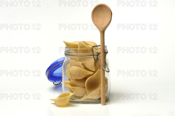 Conchiglione in glass jar with cooking spoon, Italian pasta variety