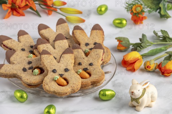 Bunny biscuits with carrots next to orange flowers and Easter bunny
