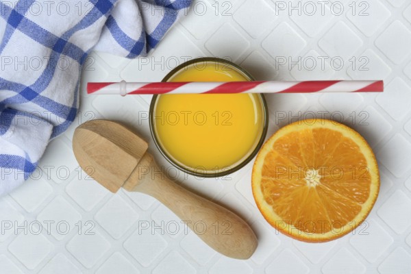 Orange juice in glass and orange, straw and citrus squeezer