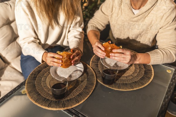 Couple sharing a moment eating burgers and drinking, probably wine or soda, sitting at a table with placemats