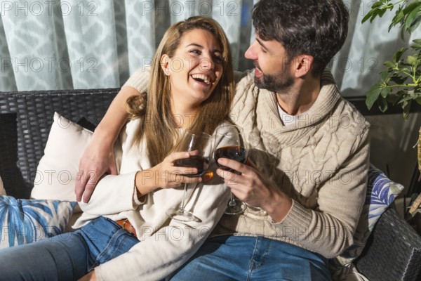 Romantic couple enjoying a relaxing evening together, sharing drinks and laughter on a comfortable sofa