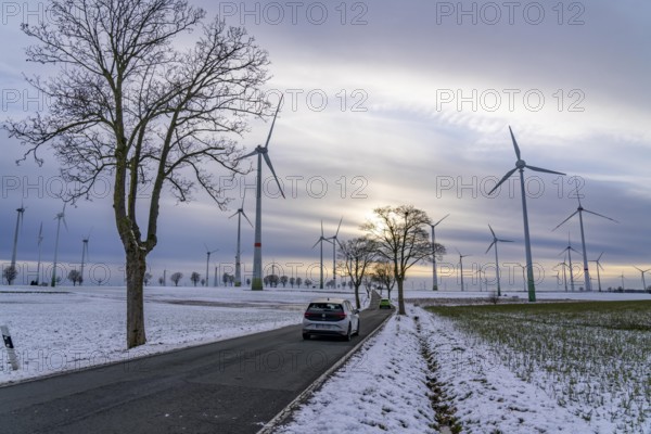 Country road, wind farm, north of Lichtenau, self-proclaimed energy town, over 190 wind turbines and over 1200 solar panels generate 10 times as much electricity as the community of 11, 900 inhabitants consumes, largest onshore cluster of wind turbines in Germany, winter, slightly snowy landscape, North Rhine-Westphalia, Germany, Europe