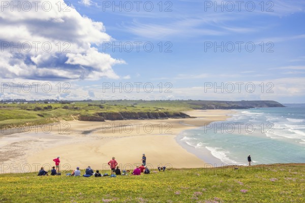 Group of hikers resting on a meadow with a scenics view at a sand beach with breaking waves and a seascape view, Plage de Lostmarc'h, Crozon peninsula, Bretagne, France, Europe