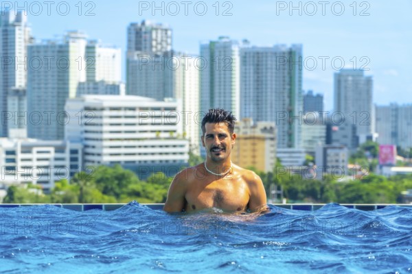 Tourist enjoying refreshing swim in rooftop infinity pool with breathtaking view of cebu city skyline, philippines