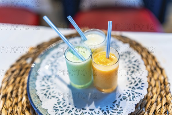 Three vibrant smoothies in glass cups with straws, placed on a decorative table setting, adding a refreshing touch to a wedding celebration