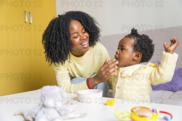 Happy african mother and cute toddler playing in the living room at home