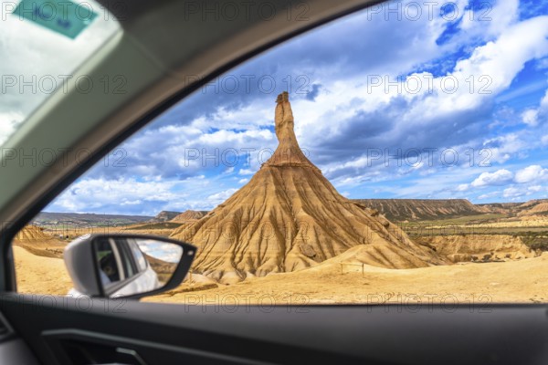 Exploring the breathtaking landscape of bardenas reales natural park in navarre, spain, admiring a unique rock formation from a car window under a cloudy sky