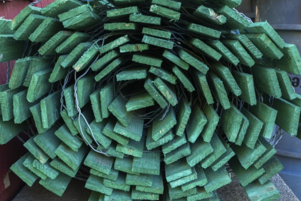 Close-up of rolled fluorescent green painted wood and steel wire snow fence in outdoor storage yard, Quebec, Canada, North America