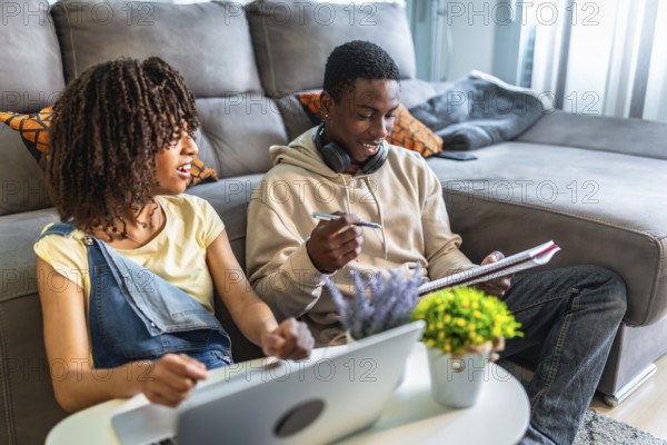 Two college students collaborating on a project, using a laptop and taking notes, demonstrating teamwork and focused learning in a comfortable home environment