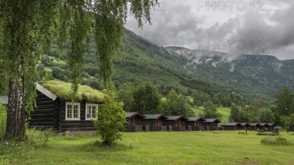 Cloudy forested ridges, wooden huts, Kirketeigen campsite, Kvam, upper Gudbrandsdal, Norway, Europe