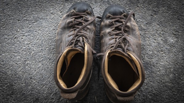 Close-up of worn leather hiking boots on dark ground, pilgrimage route Olavsweg or Olavsleden, Hamar, Norway, Europe