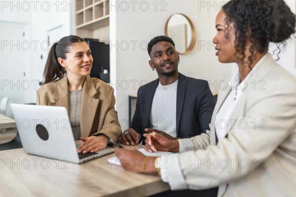 Business team discussing project during a meeting in modern office using laptop, taking notes and smiling
