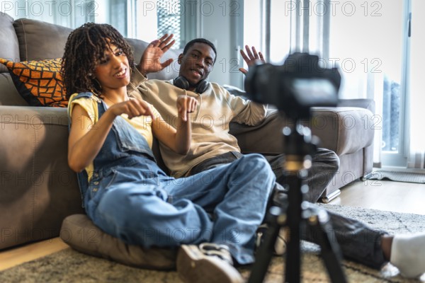 Two influencers recording a lively vlog in their cozy living room, gesturing enthusiastically and pointing towards their camera setup