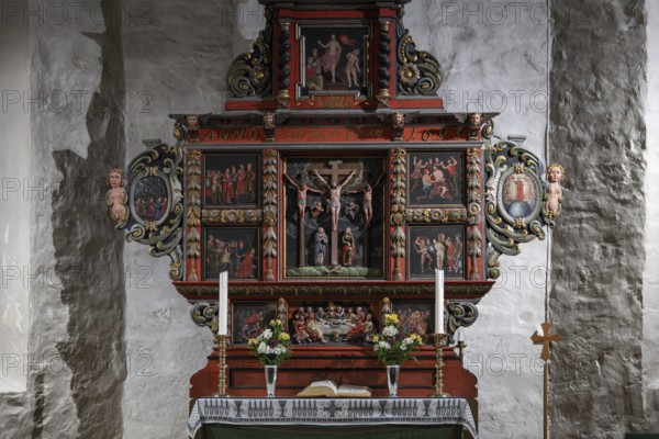 Richly decorated wooden altar in front of a stone wall, adorned with images of saints, candles and flowers, Skedsmo Pilgrims' Church, Skedsmokorset, Norway, Europe