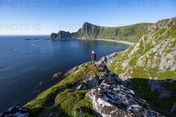 Mountaineer with view of coastal landscape, steep coast with peak Måtind, Høyvika beach and sea, hike to the peak of Måtind, Andøya island, Vesterålen, Nordland Norway