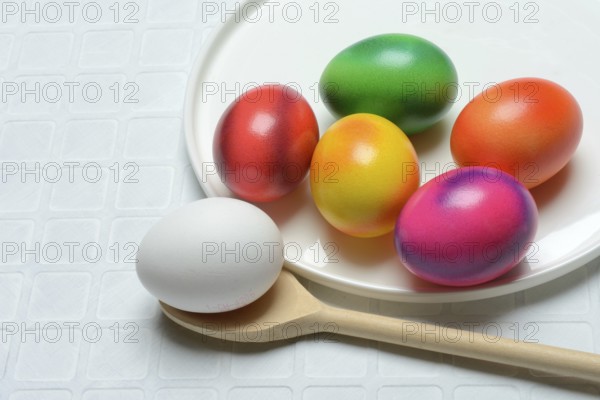 Coloured eggs on a plate and uncoloured eggs on a spoon, Easter celebration
