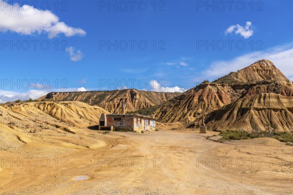Scenic view of an abandoned, graffiti covered building rising from the arid bardenas reales desert in navarre, spain, under a vivid blue sky