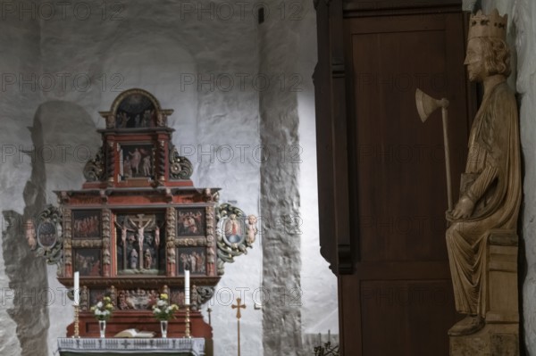 Richly decorated wooden altar in front of a stone wall, decorated with images of saints, wooden sculpture of Olav the Saint or Olav II Haraldsson with axe, Skedsmo Pilgrim Church, Skedsmokorset, Norway, Europe