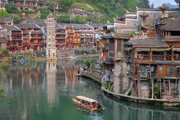 Chinese tourist attraction destination, Feng Huang Ancient Town (Phoenix Ancient Town) on Tuo Jiang River with Wanming Pagoda tower and tourist boat. Hunan Province, China, Asia