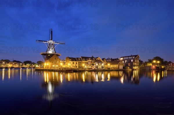 View of Harlem cityscape with landmark windmill De Adriaan on Spaarne river in the night illuminated. Harlem, Netherlands