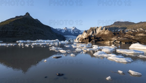 Reflection in the Svínafellslon glacier lagoon with ice floes, Svínasfellsjökull glacier tongue, glaciated mountain peak Hrútfjallstindar in the background, at sunset, Svínafell, Iceland, Europe