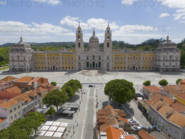 Historic baroque-style palace with yellow façade and two towers, under blue sky and large square, Aerial view, Palace, Palácio Nacional de Mafra, Lisbon, Lisboa, Portugal, Europe