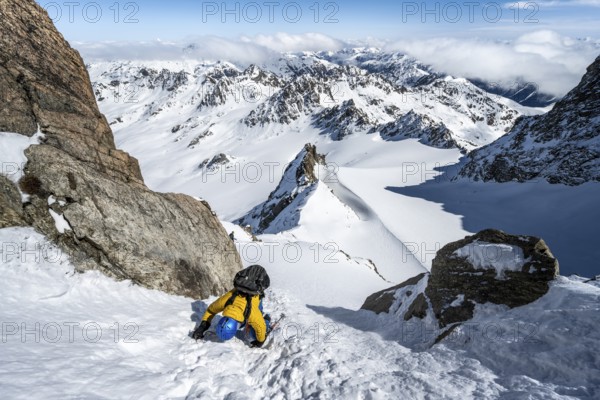 Mountaineer with ice axe and crampons, ascent through steep snowfield to Piz Kesch or Piz d'Es-cha in winter, view of mountain panorama with Vadret da Porchabella glacier, Albula Alps, Rhaetian Alps, Grisons, Eastern Switzerland, Switzerland, Europe