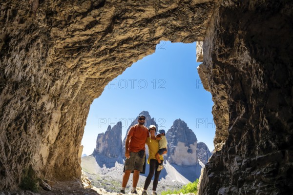Family enjoying breathtaking view of tre cime di lavaredo, dolomites, italy, during summer hike, framed by a Tre Cime Cave entrance