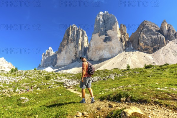 Hiker enjoying the breathtaking view of the tre cime di lavaredo peaks during a sunny summer day in the dolomites, italy