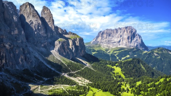 Breathtaking summer landscape in the dolomites, featuring a winding road through lush green valleys and towering peaks