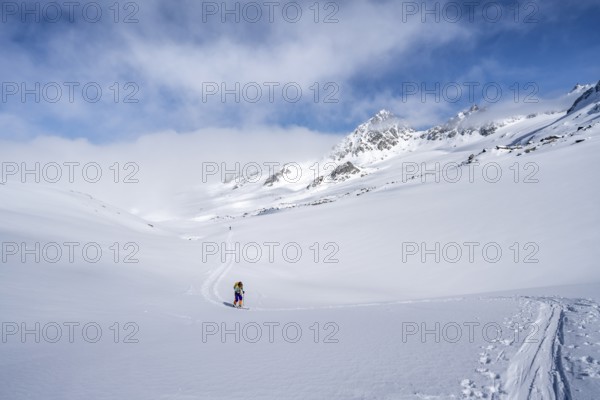 Ski tourer ascending through a picturesque snow-covered mountain landscape with views of mountain peaks, ascent to the summit of Kesch Pitschen, Bündner Haute Route ski tour, Albula Alps, Rhaetian Alps, Grisons, Eastern Switzerland, Switzerland, Europe