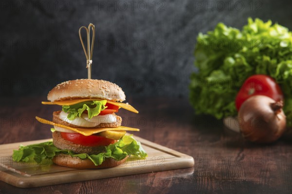A burger on a wooden board, with fresh ingredients in the background in a rustic ambience