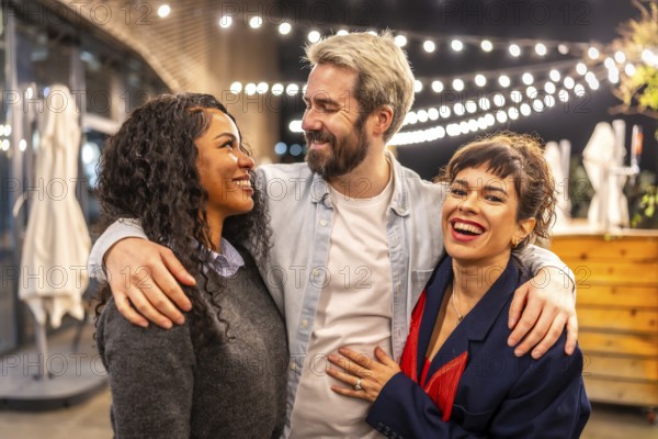 Happy multi-ethnic coworkers embracing while celebrating party in a bar terrace outdoors after work at night