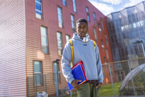 African american student backing to university standing outdoors and looking serious at camera
