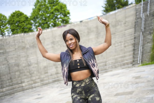 Latin beauty sensual woman raising hands dancing salsa alone in a city
